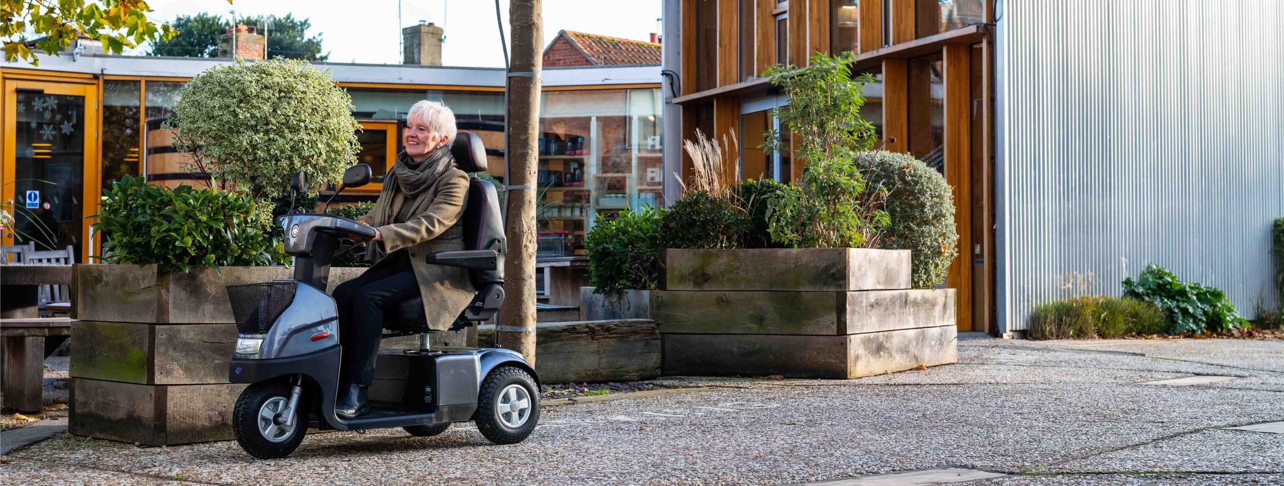 An older woman riding a 3 wheel mobility scooter