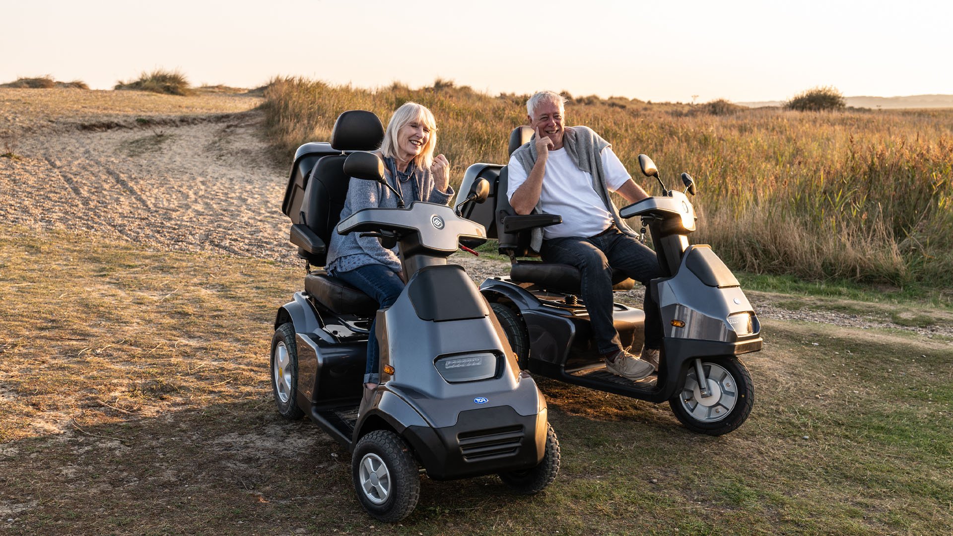 A woman on a 4 wheel mobility scooter and a man on a three wheel mobility scooter