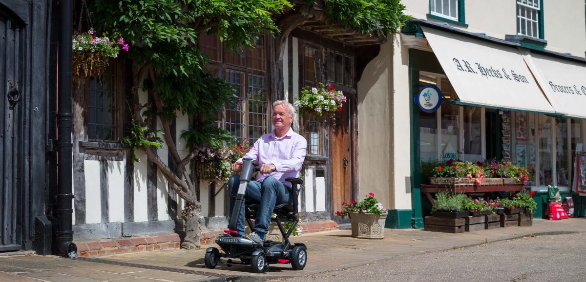 An older man using a mobility scooter on a street pavement