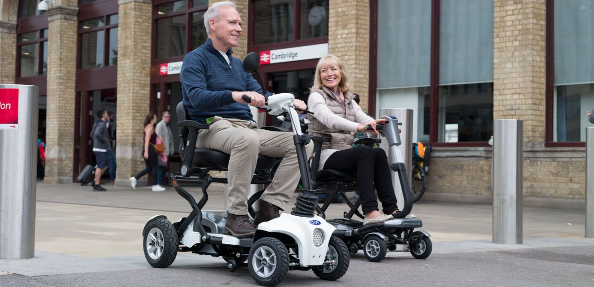 A man and a woman on Maximo Plus folding mobility scooters