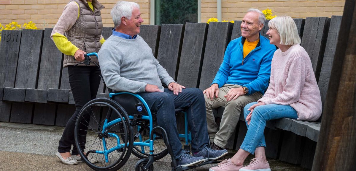 A group of friends talking and one is in a Strongback wheelchair