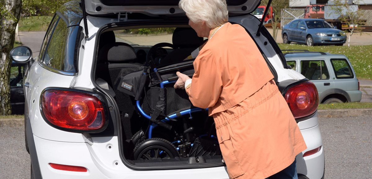 A Strongback wheelchair being packed into a car boot