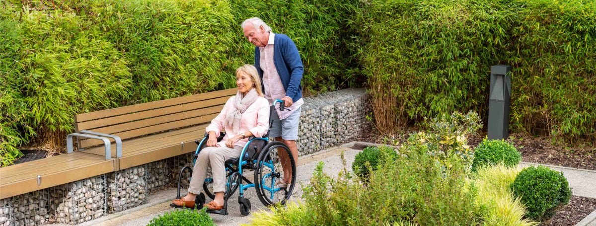 An older man pushing a woman in a wheelchair